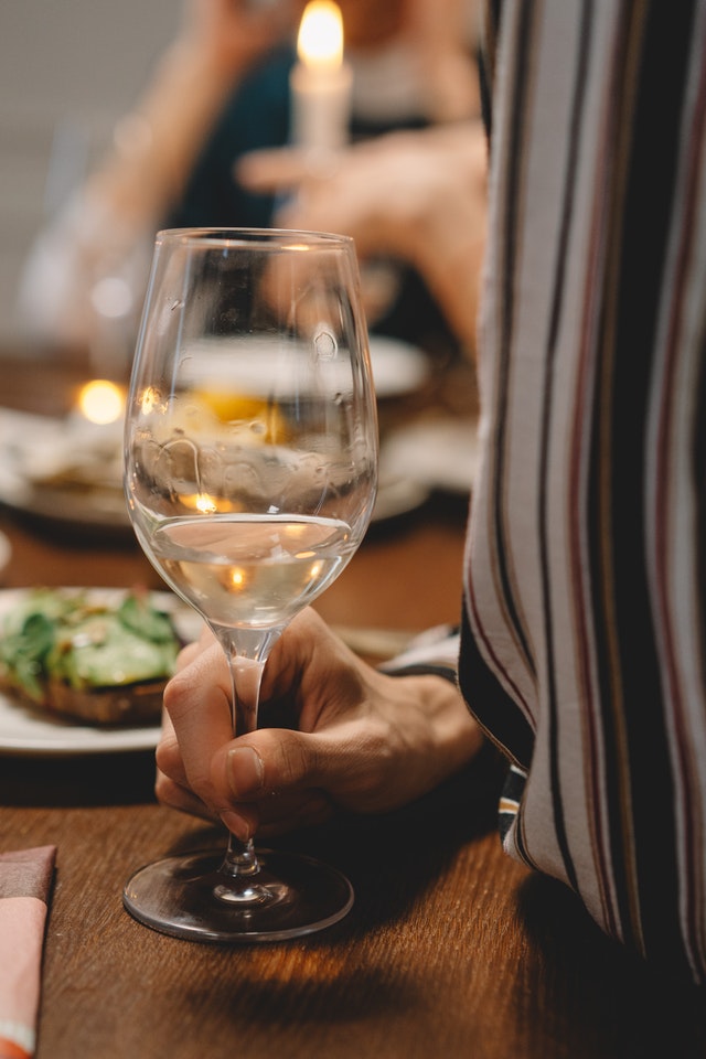 glass of white wine with food on a table