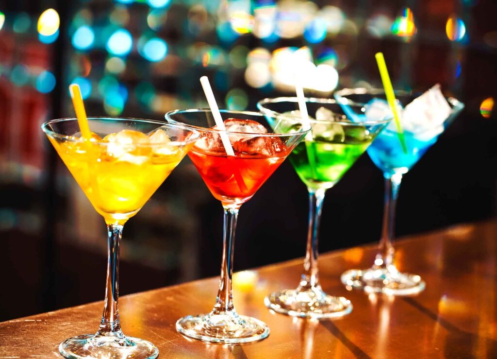rainbow colored martinis on a bar