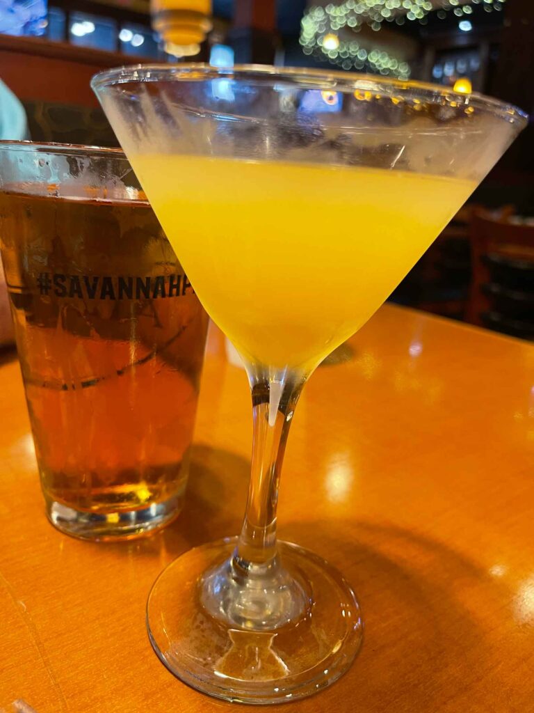 cocktail in martini glass and pint of beer on wooden table