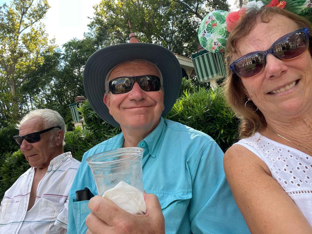 enjoying a pint of beer in England at Epcot sitting on a bench the three of us