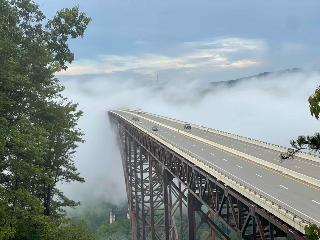 New River Gorge Bridge taken from top view with the ends of the bridge in fog