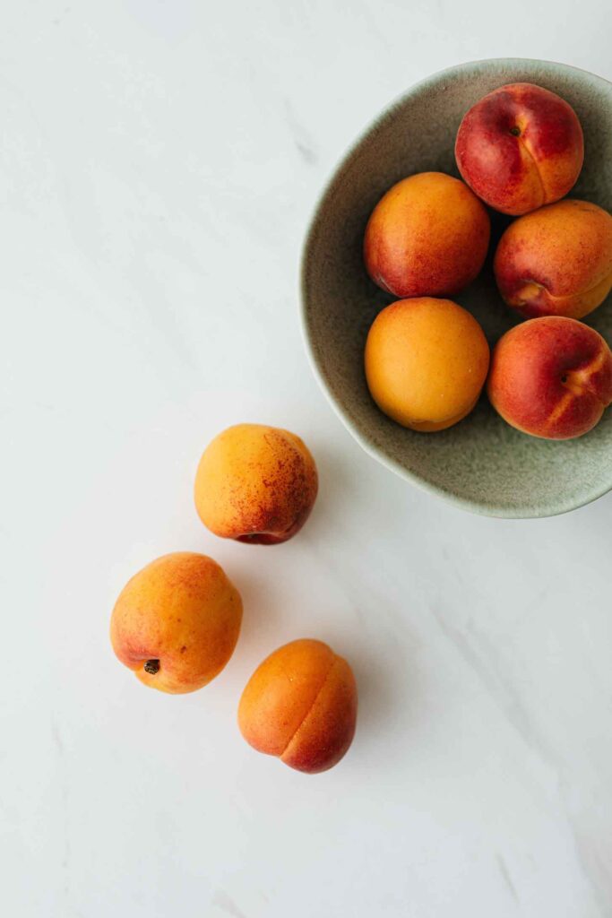 peaches in a bowl spilling out over onto a counter