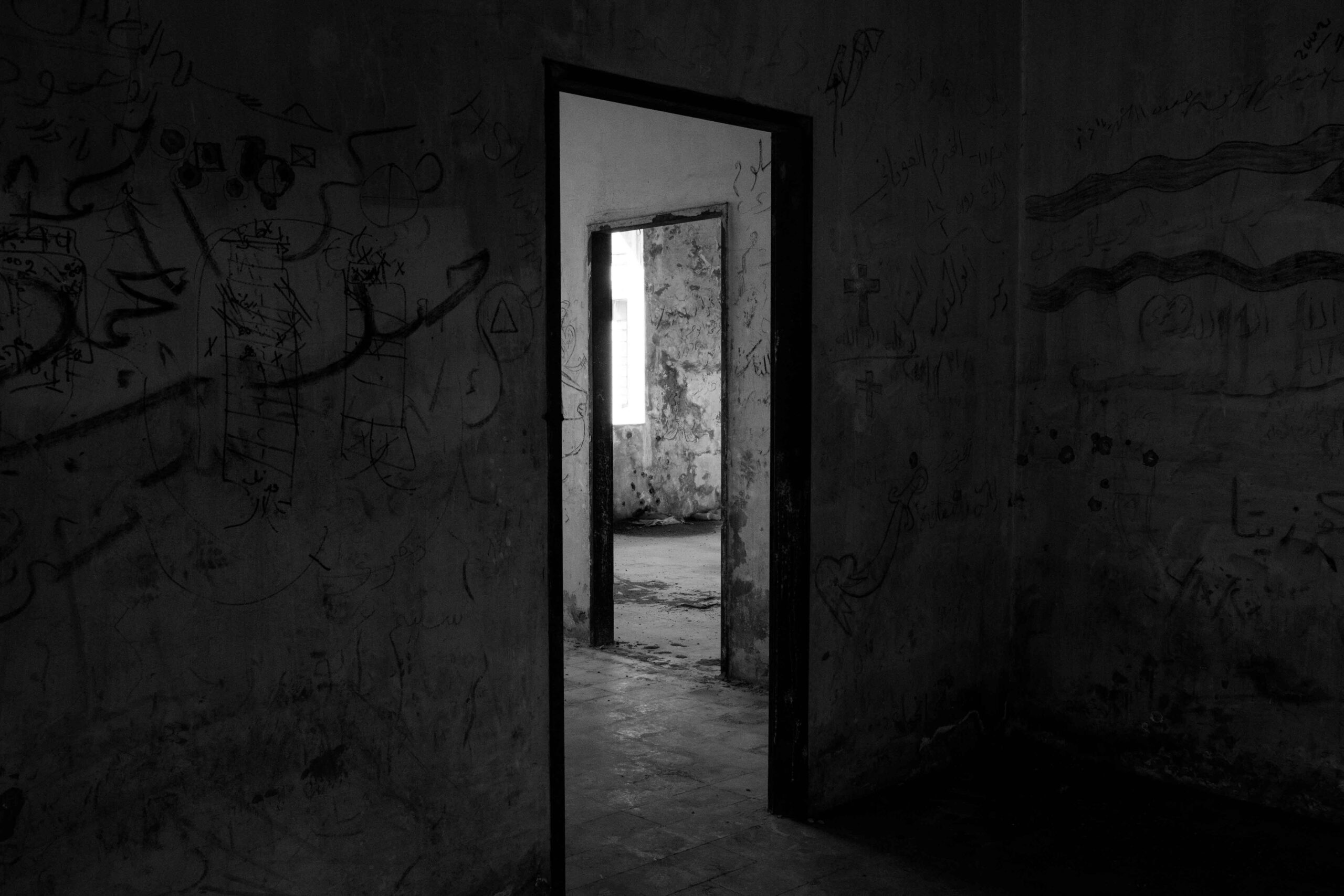 black and white picture of a hallway with doors. looks very spooky