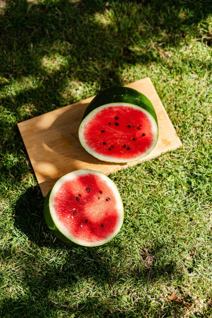 watermelon sliced in half on a wood cutting board on the grass.  Florida watermelon farms